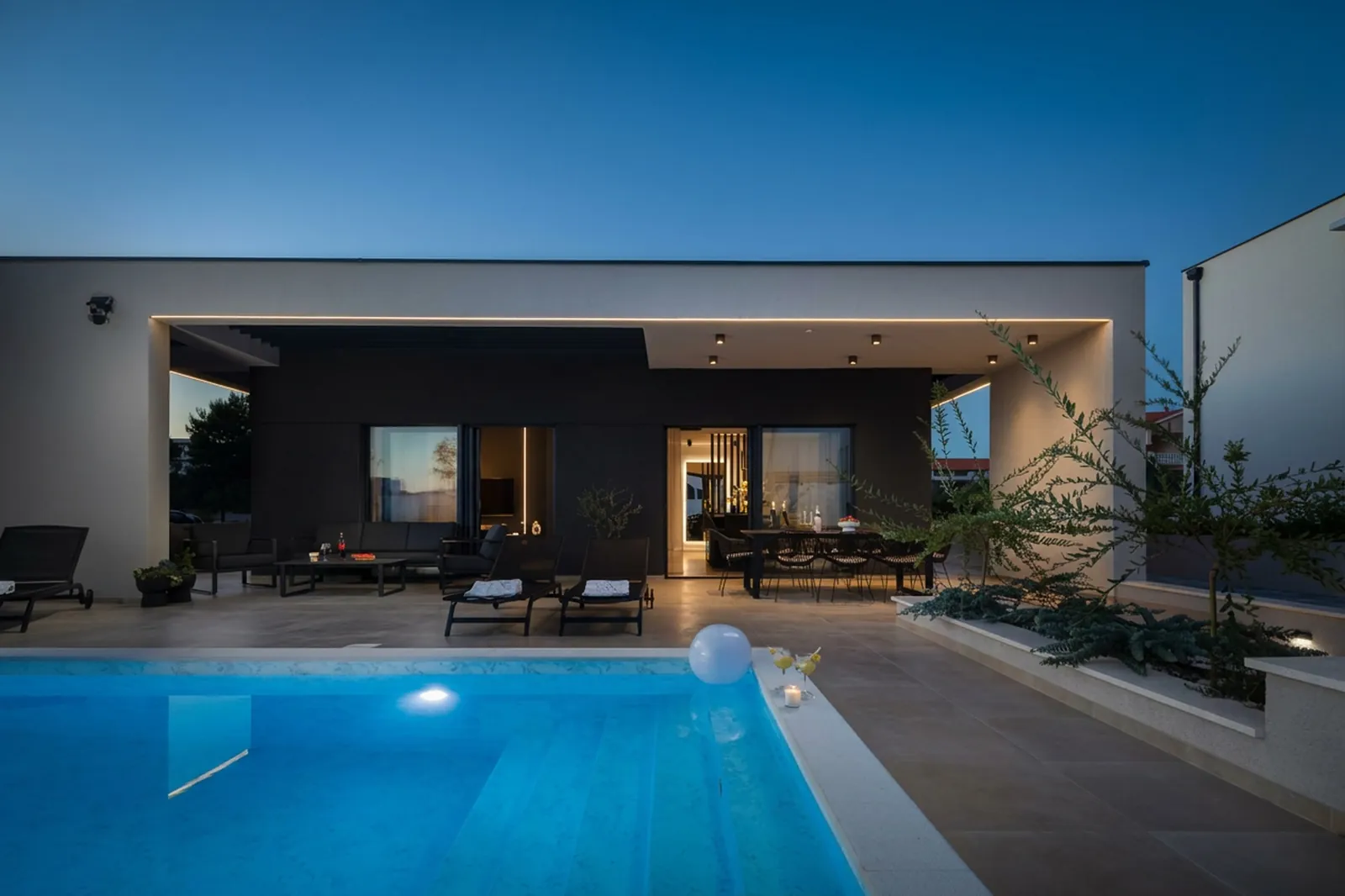 Villa M private pool at dusk with the terrace lounge glowing behind it