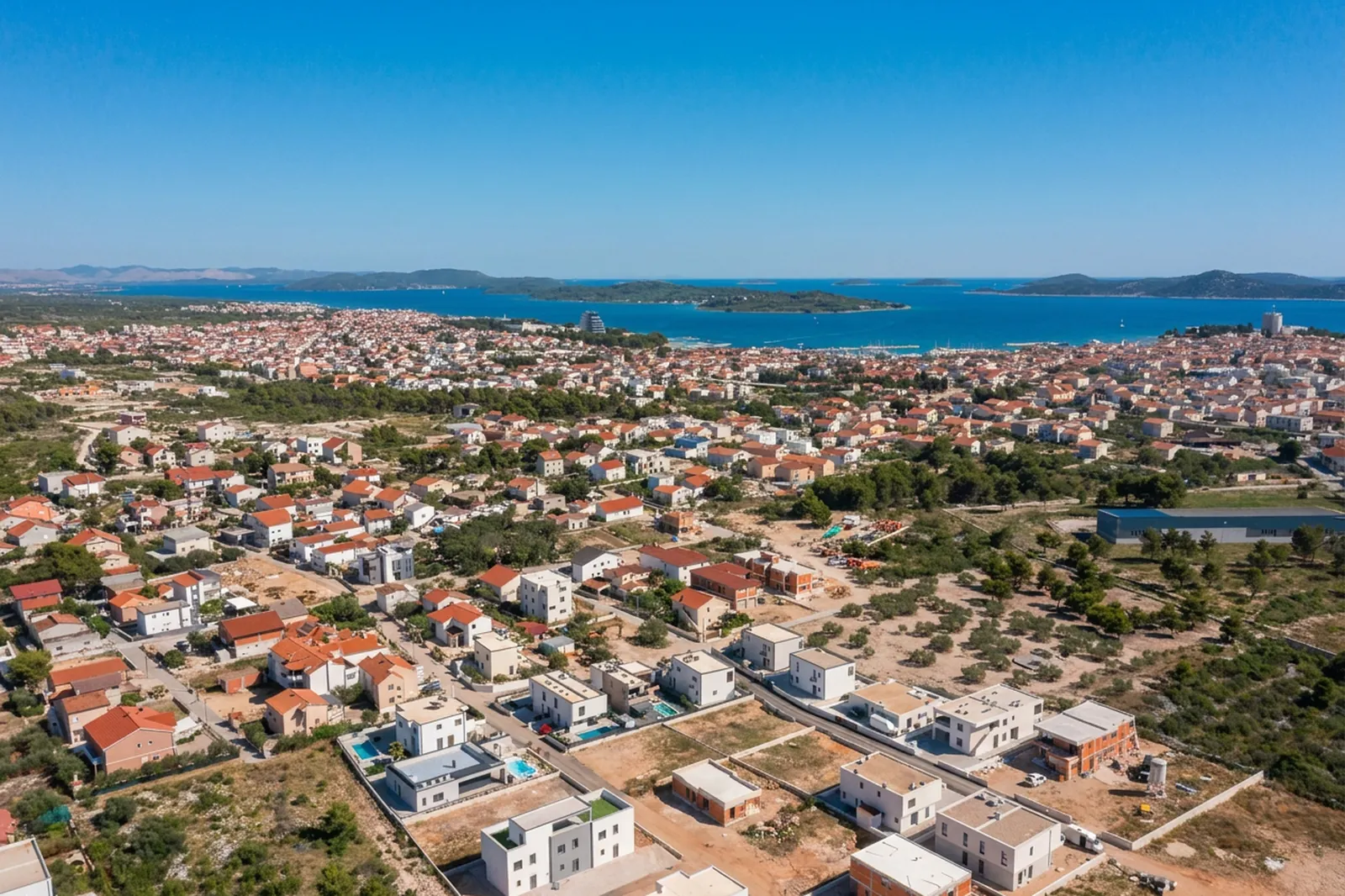 Aerial over Vodice rooftops toward the sea and islands