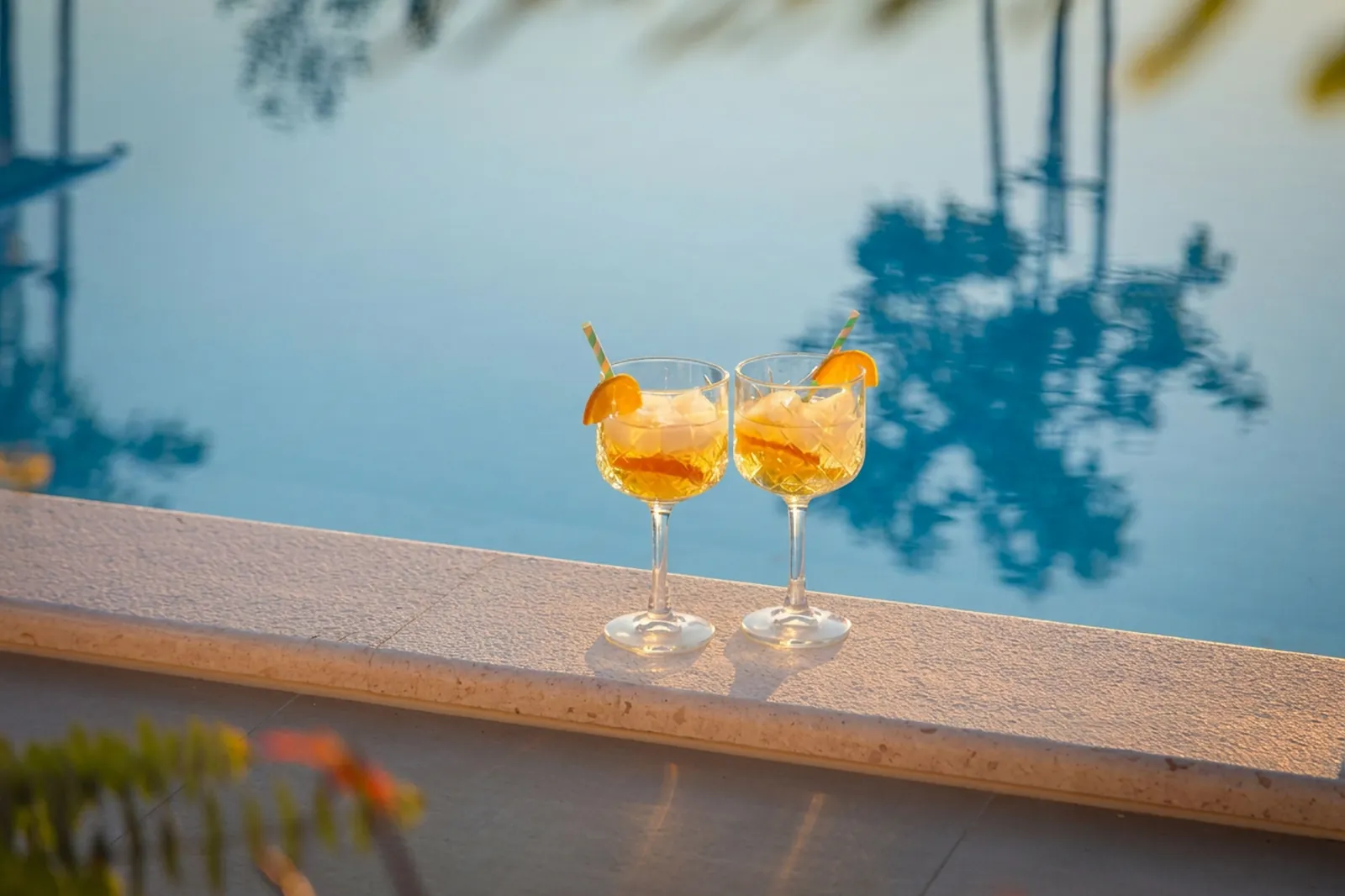 Two spritz cocktails resting on the pool edge