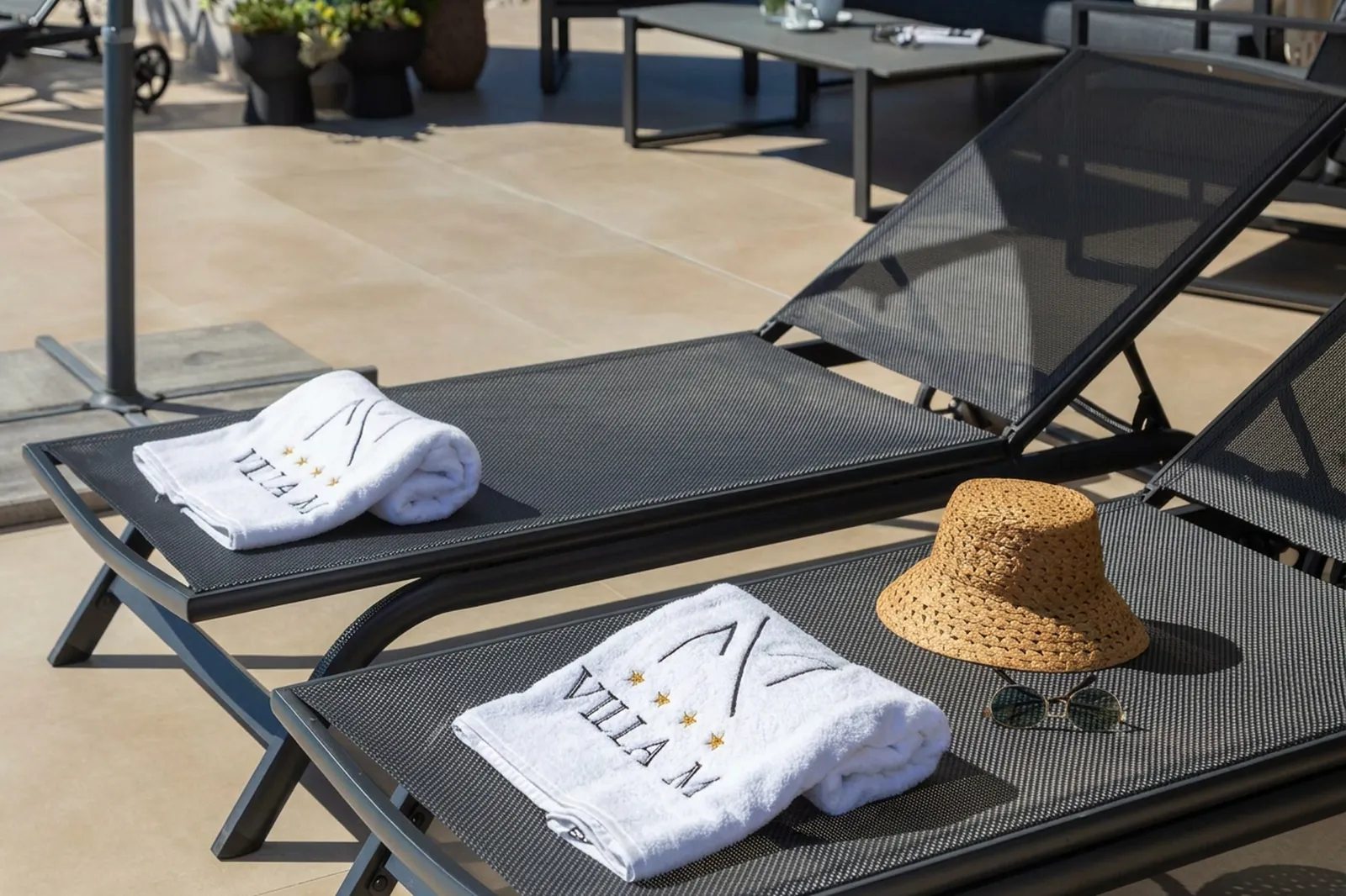 Sun loungers with folded towels and a straw hat beside the pool