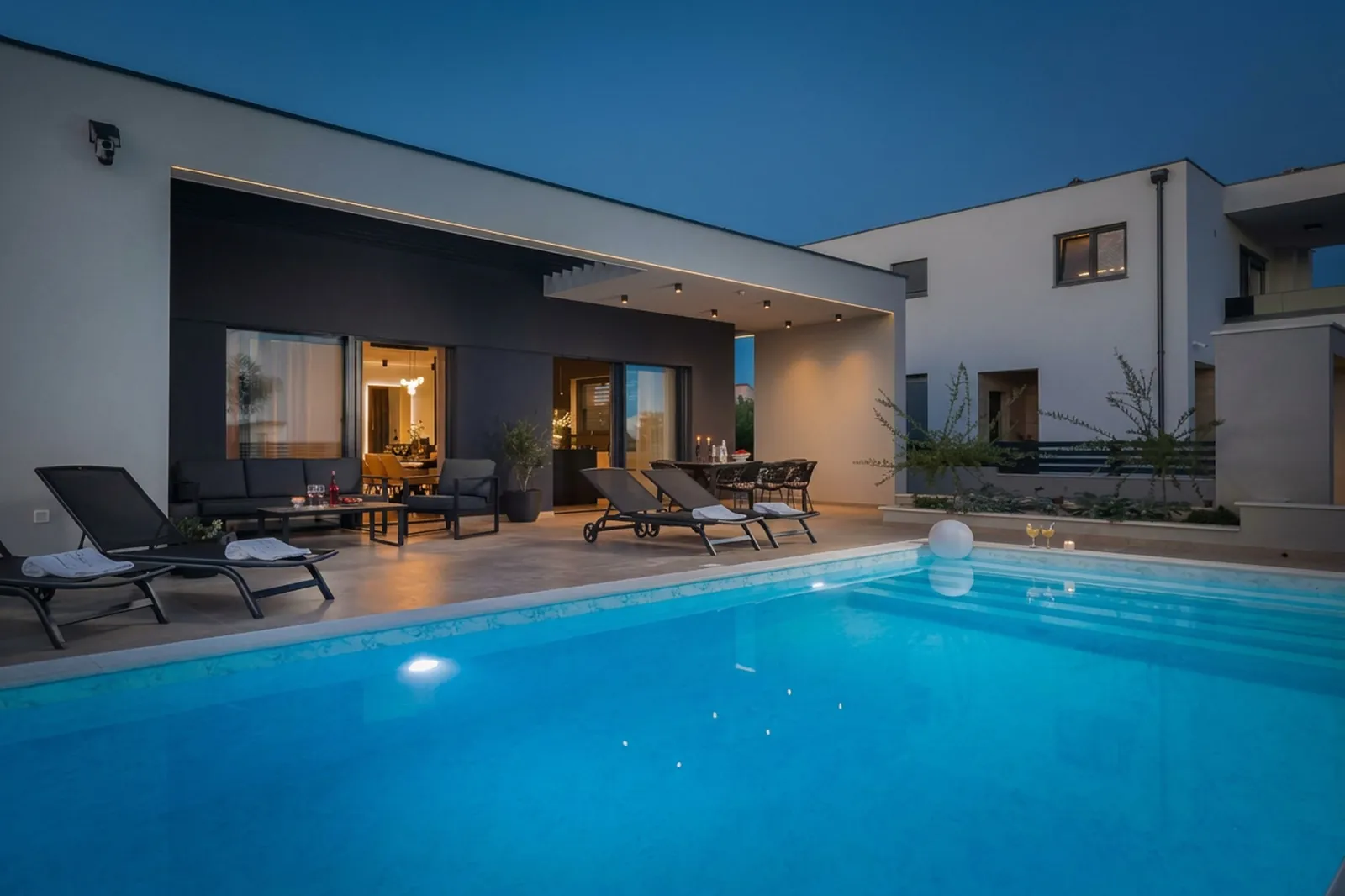 Illuminated villa mirrored in the pool during blue hour
