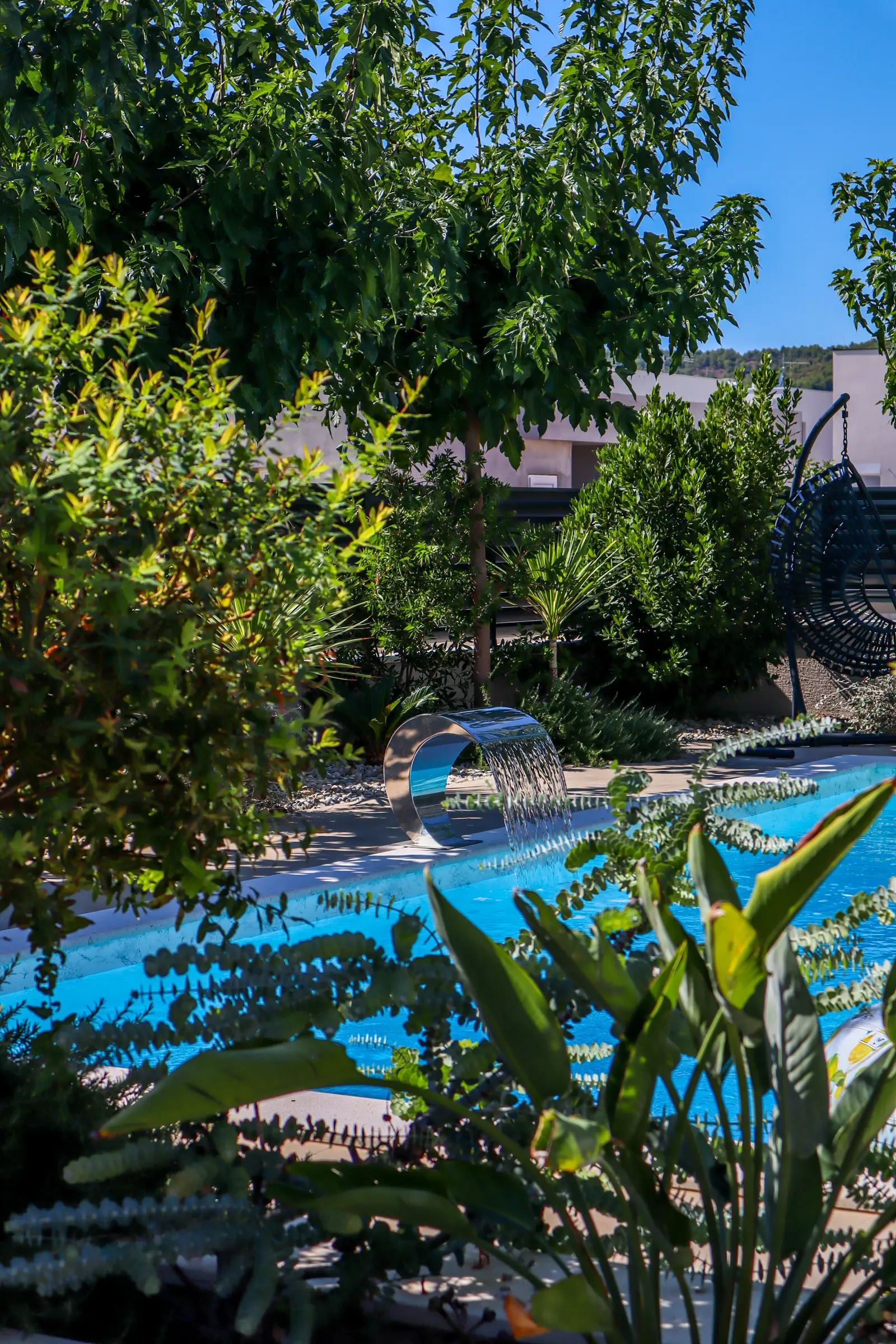 Vertical view of the pool and waterfall spout framed by shrubs